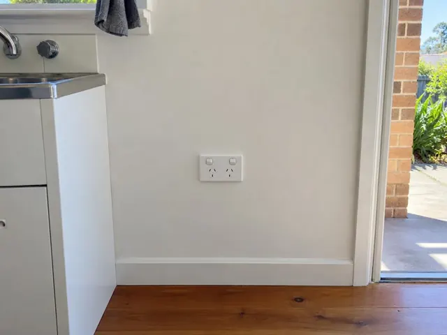 Double power point on a painted wall beside a sink and timber floor in Caves Beach