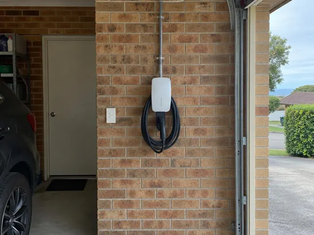 EV charger mounted on a brick garage wall beside a doorway in Swansea Heads